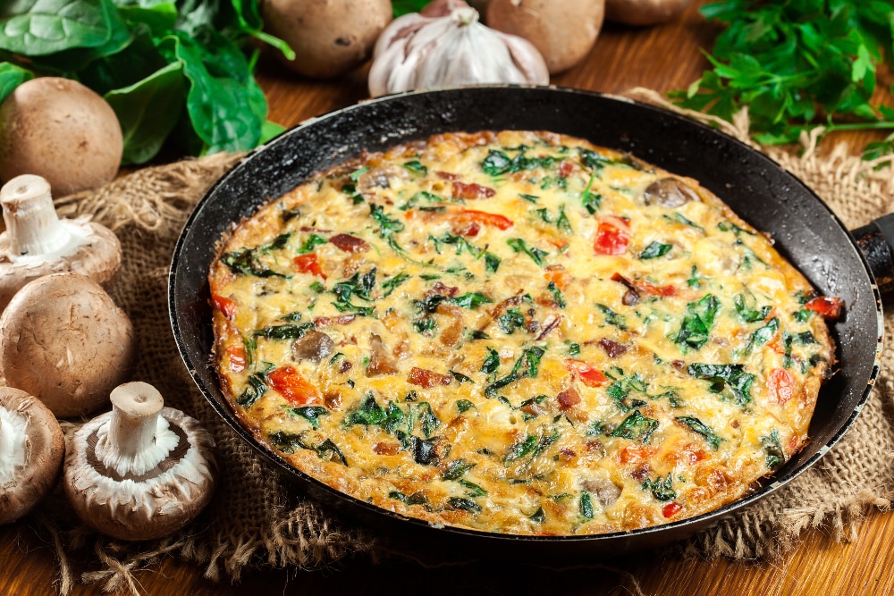 An omelet with spinach, tomatoes, and mushrooms.