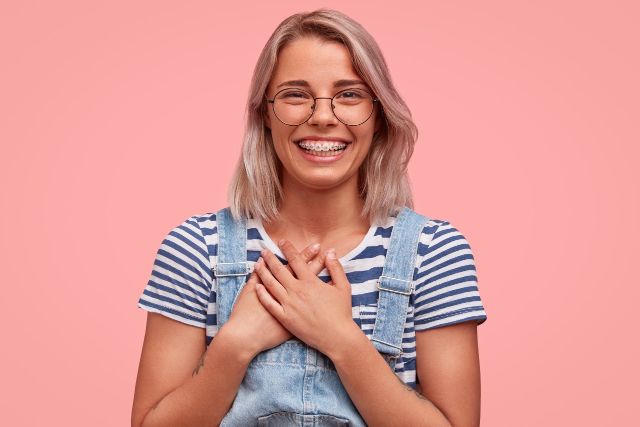 A young woman with braces looks toward the camera and laughs.